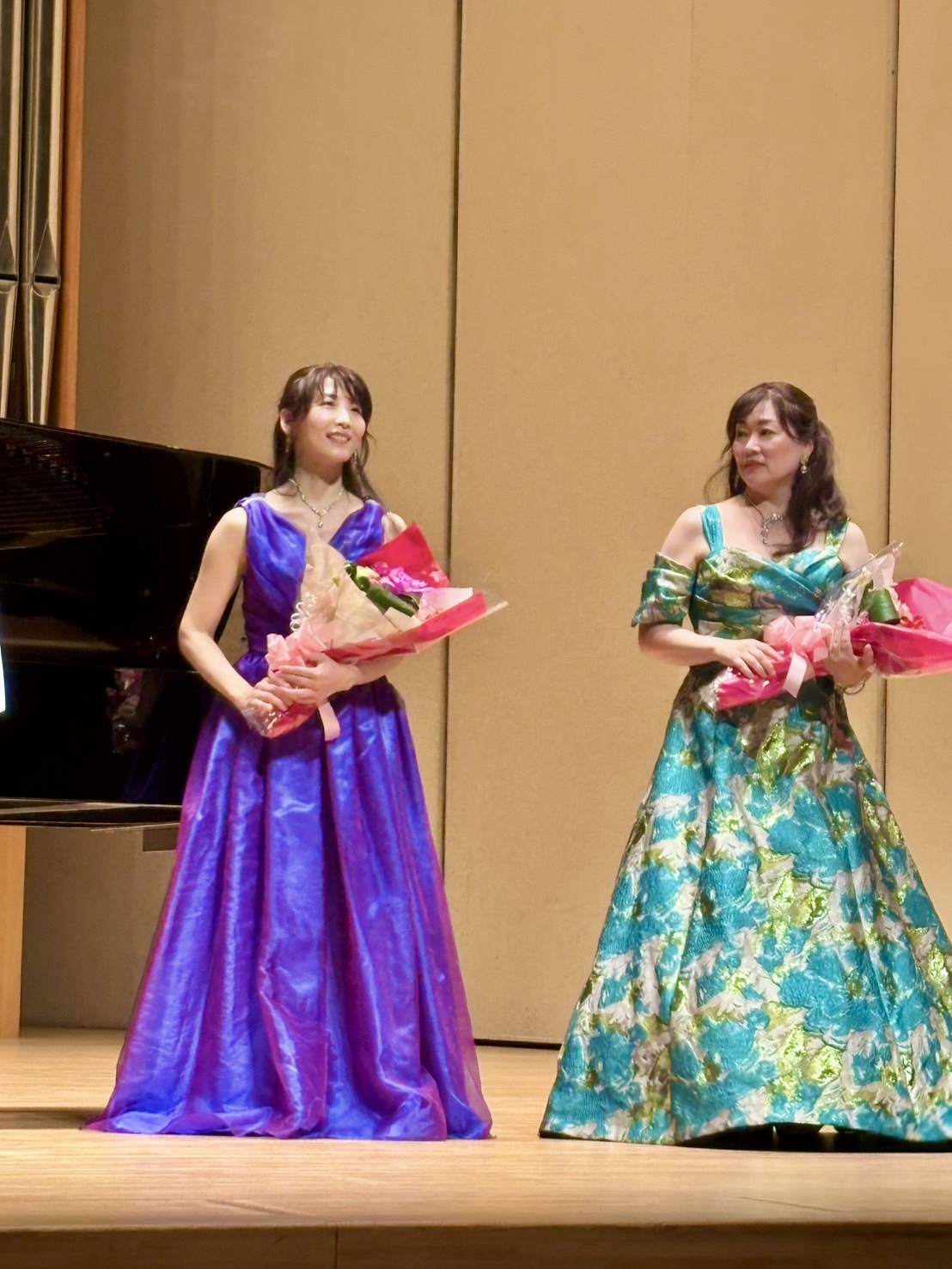 ソプラノ歌手の氏家和歌子さんとピアニストの藤波結花による、中新田バッハホールでの花束贈呈シーン。華やかなグリーンと紫のドレス姿。